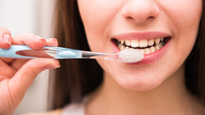 Smiling woman's mouth with toothbrush ready to be used.