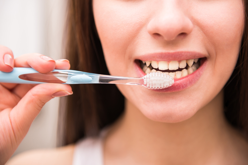 Smiling woman's mouth with toothbrush ready to be used.